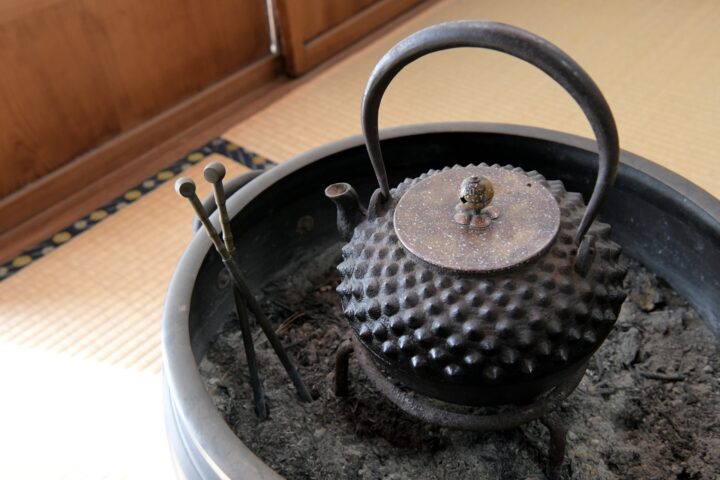 丸い火鉢の上の使い込まれた鉄瓶と蓋